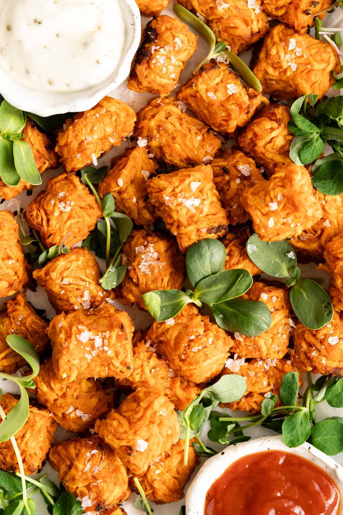 Overhead view of sweet potato tater tots on platter with dipping sauces