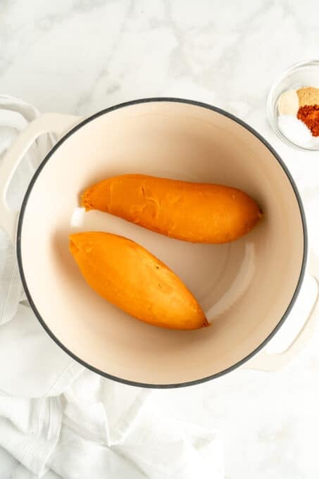 Overhead view of cooked and peeled sweet potatoes in white pot