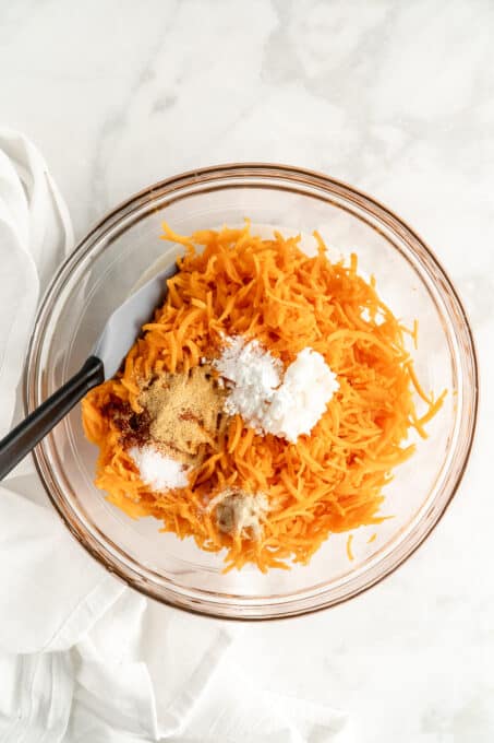 Shredded sweet potato and other tater tot ingredients in glass bowl