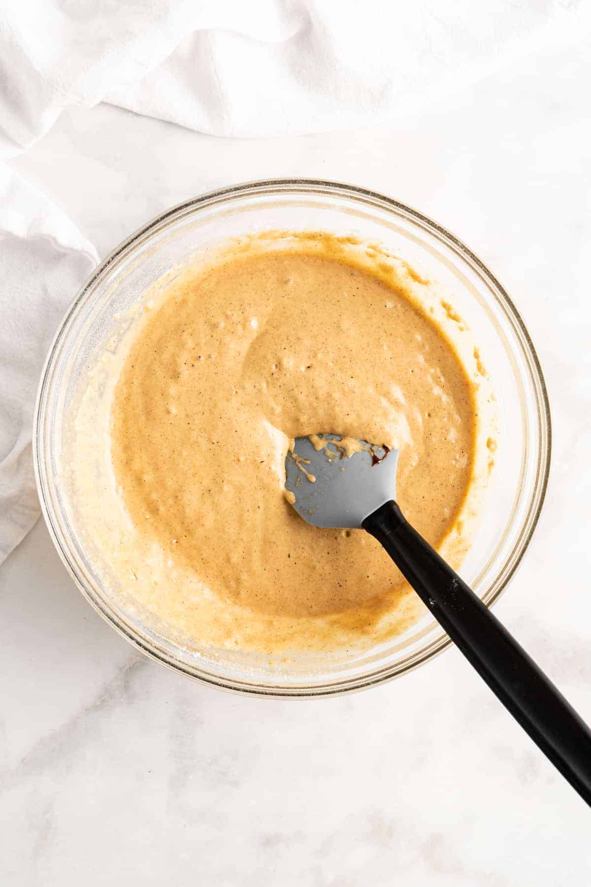 Pancake batter in glass mixing bowl with plastic spoon