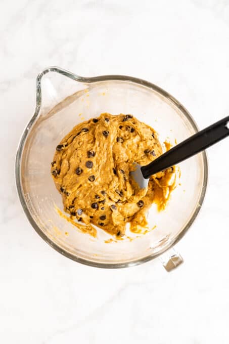 Overhead view of pumpkin bread batter in glass mixing bowl with spatula
