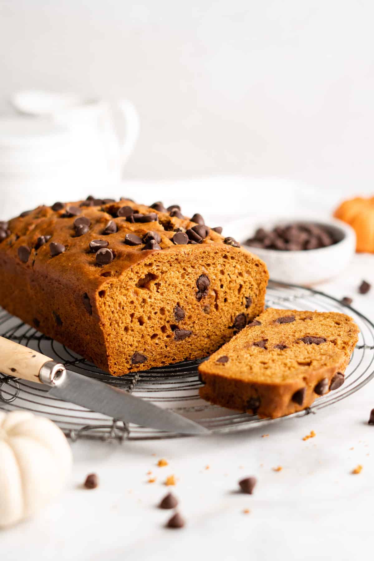 Loaf of pumpkin bread on cooling rack with knife, with one slice cut