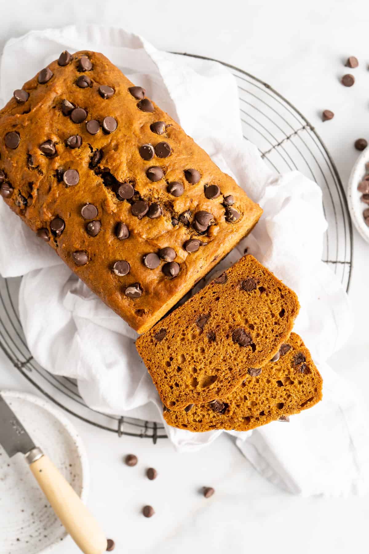 Chocolate chip pumpkin bread on cooling rack with two cut slices