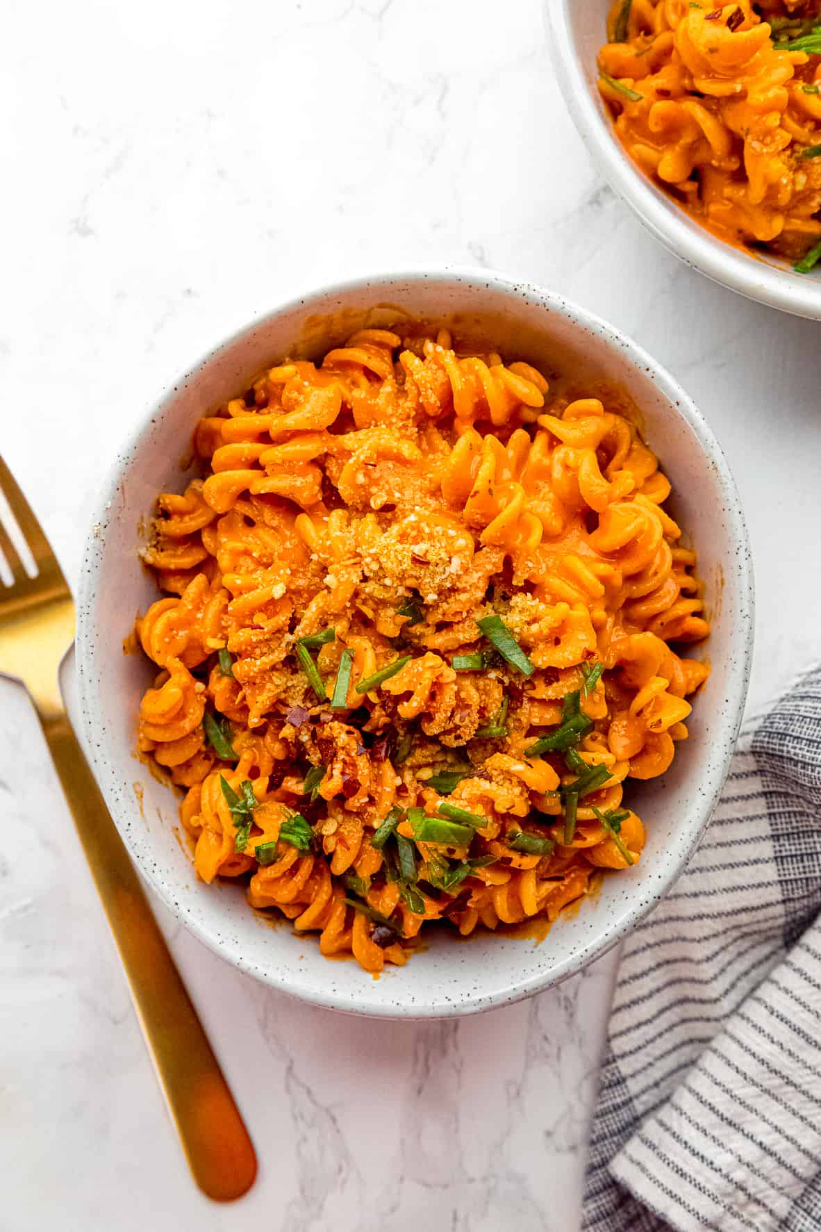 Overhead view of roasted red pepper pasta in a bowl next to a fork.