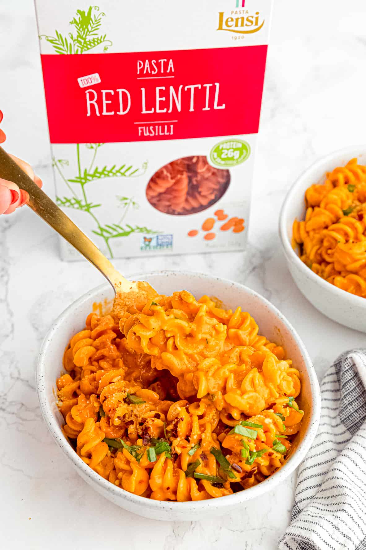 roasted red pepper pasta with a spoon lifting some out with box of pasta in background