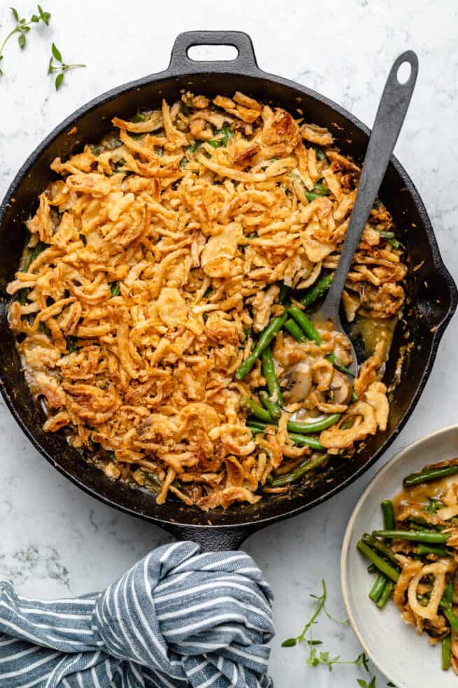 Overhead shot of vegan green bean casserole in cast iron skillet with spoon