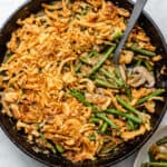 Vegan green bean casserole in cast iron skillet with spoon for serving