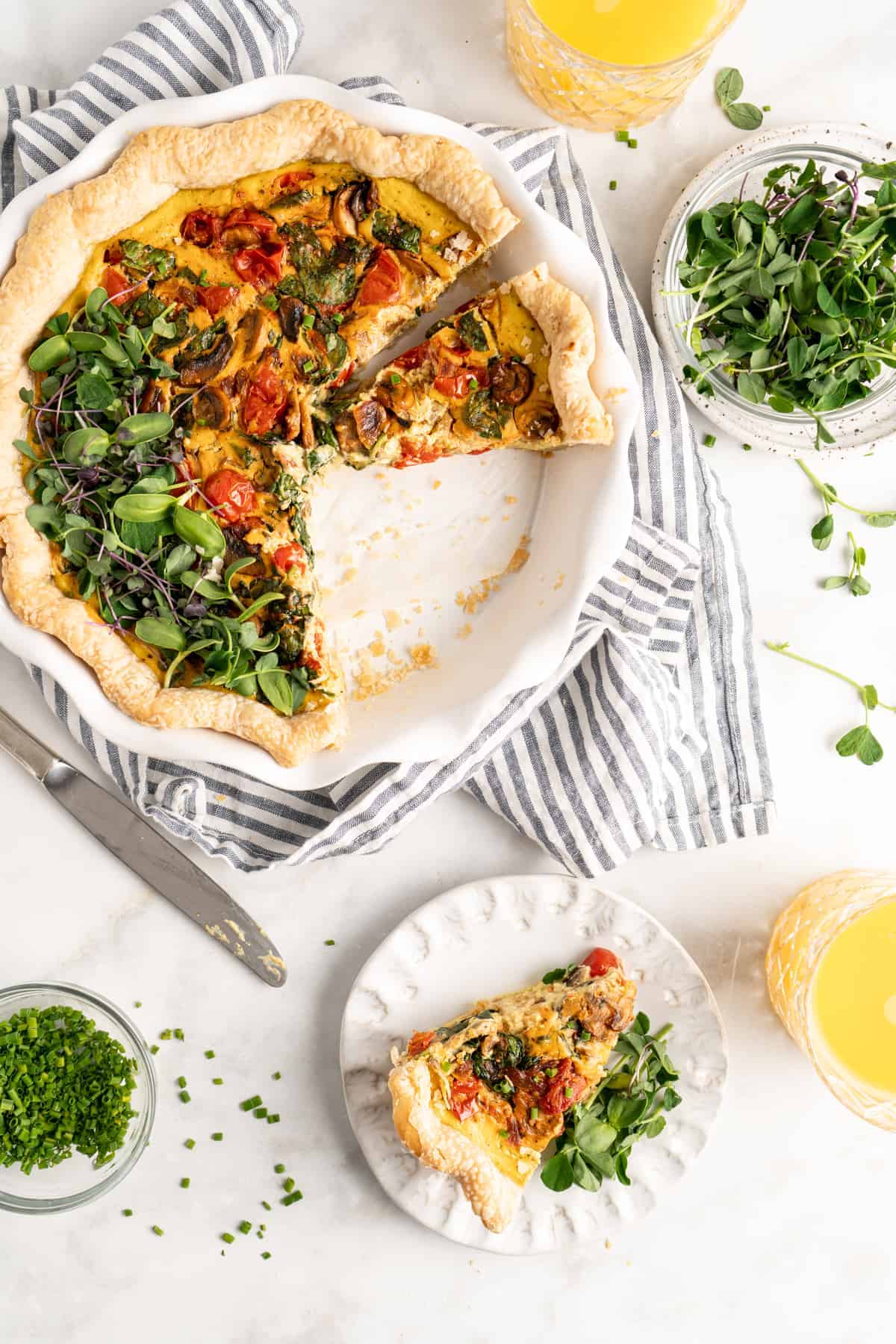 Overhead view of vegan quiche in baking dish with one slice plated