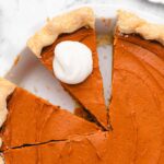 sweet potato pie with two slices cut, one with vegan whipped cream on top