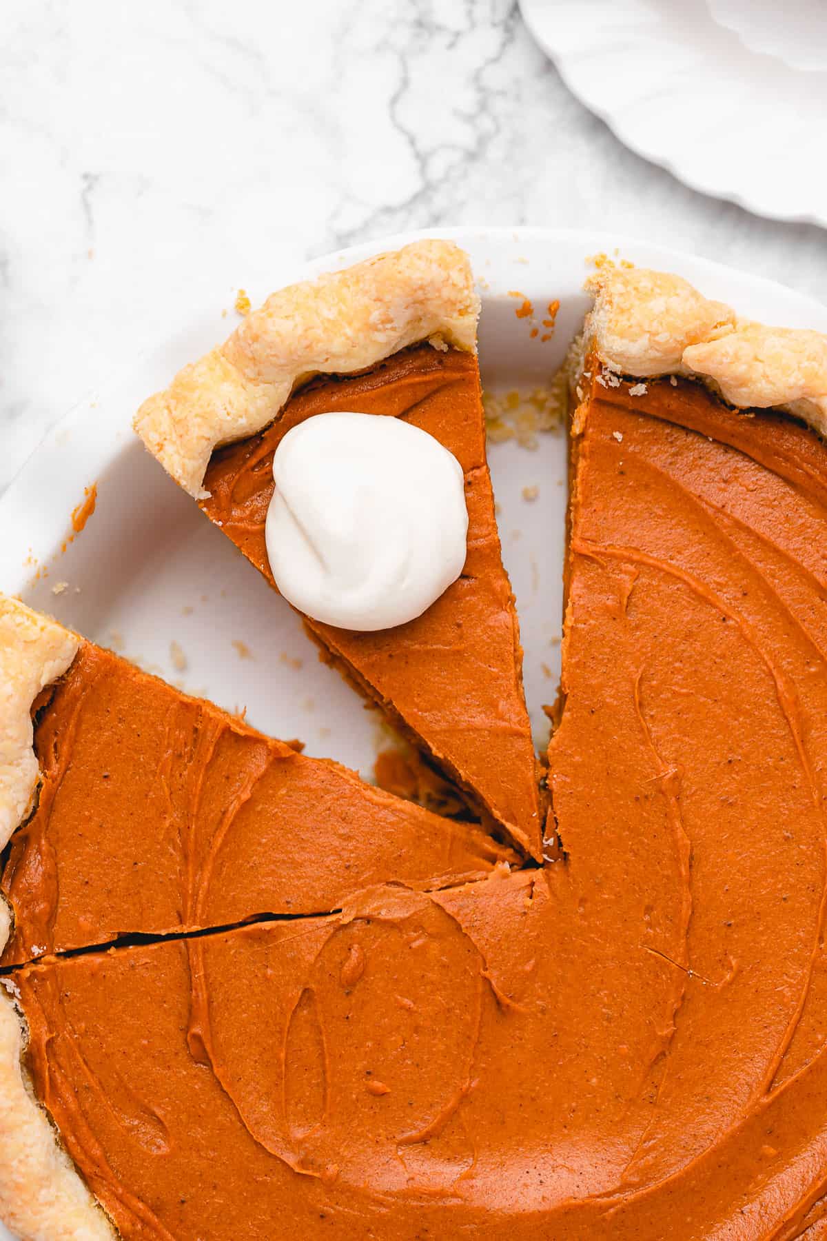 sweet potato pie with two slices cut, one with vegan whipped cream on top