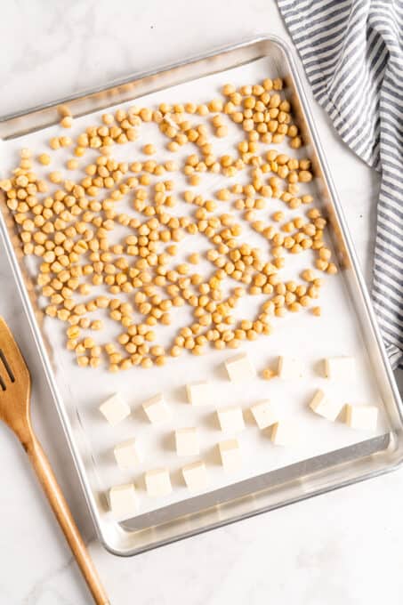 Overhead view of chickpeas and tofu on a parchment lined sheet pan.