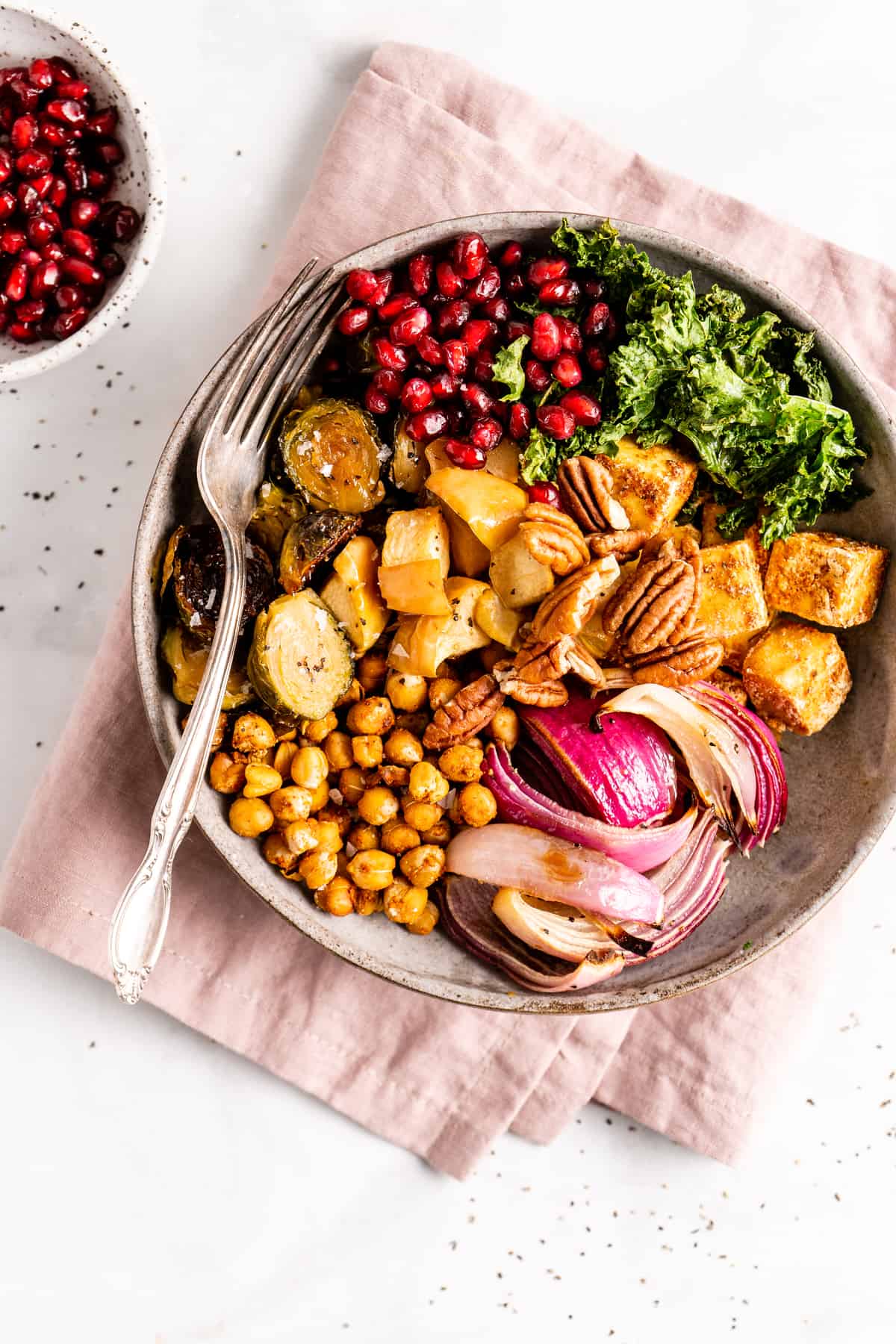 Overhead view of a vegan Buddha bowl on a folded pink napkin with a fork.