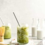 Iced matcha latte in glass tumbler with stainless steel straw
