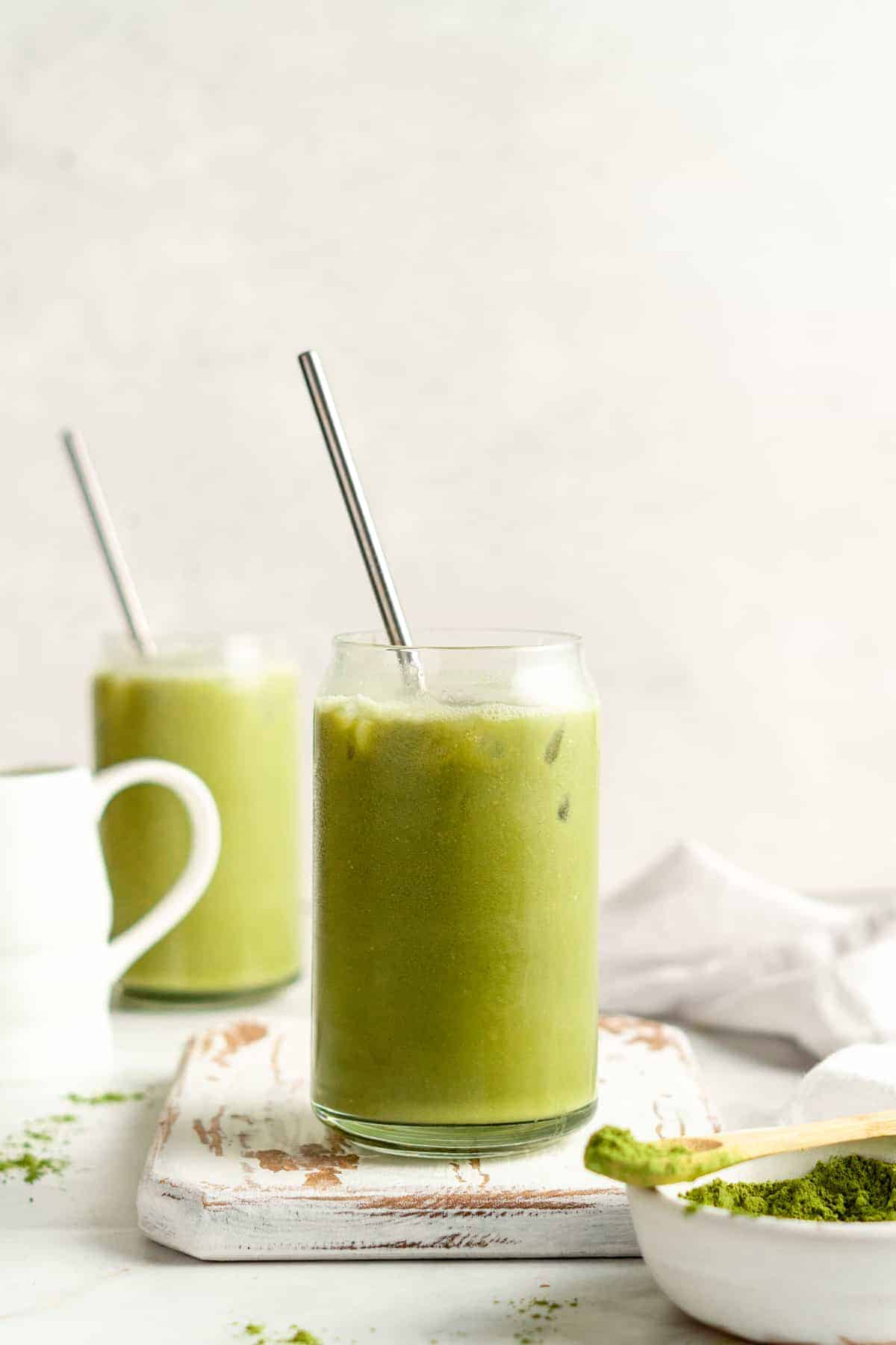 Two iced matcha lattes in glass tumblers with stainless steel straws