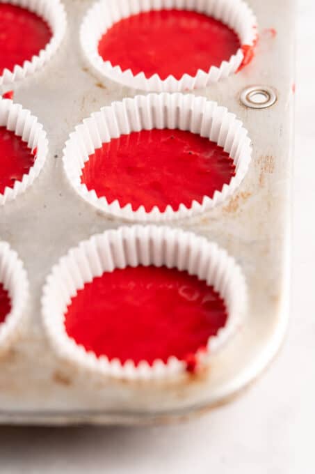 Closeup of red velvet cake batter in cupcake tin before baking