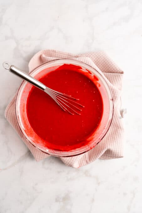 Overhead view of red velvet batter in mixing bowl with whisk