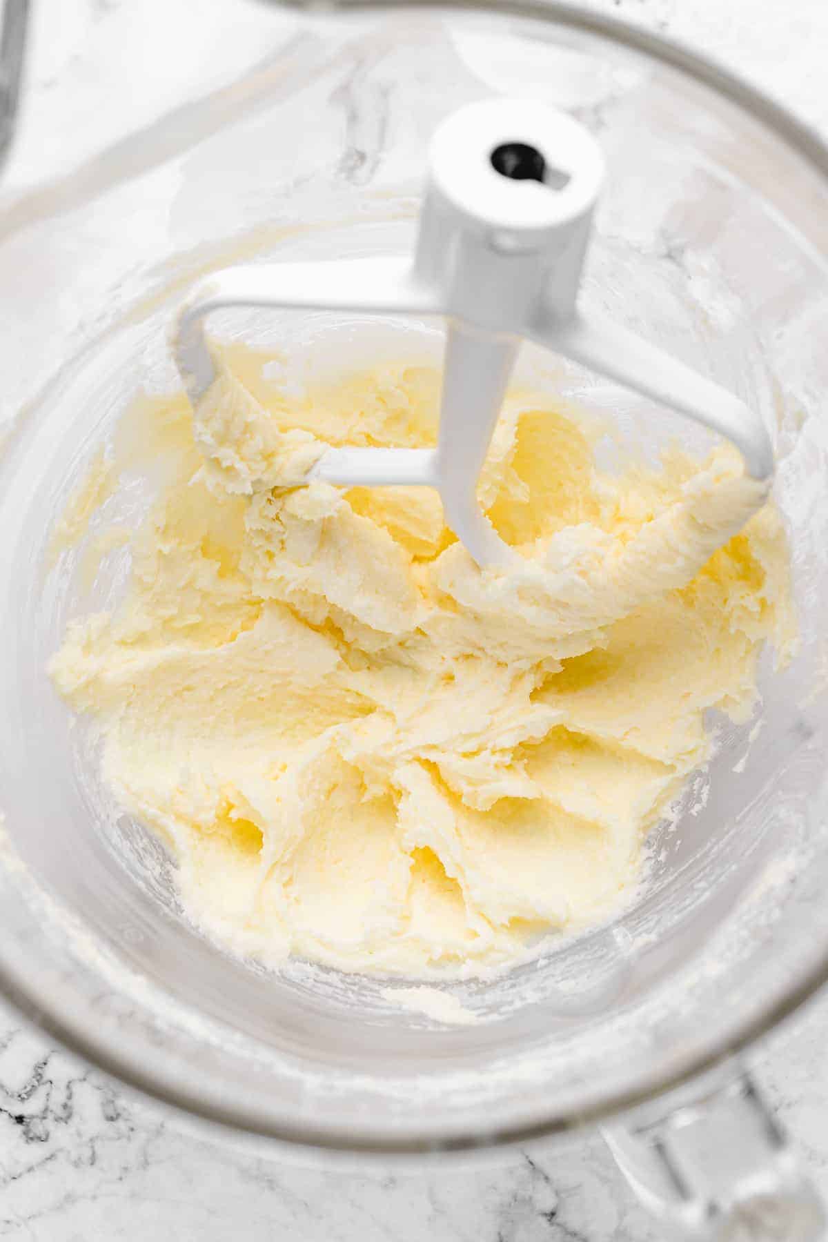 Butter and sugar being creamed in glass stand mixer bowl