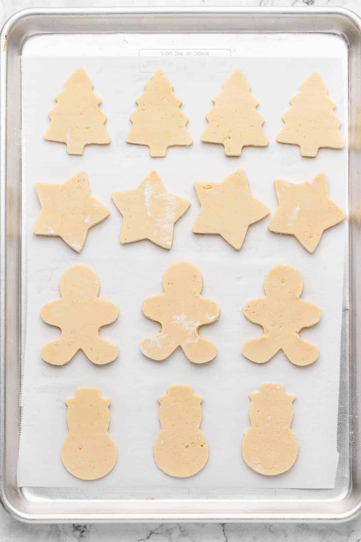Overhead view of cut sugar cookie dough on parchment-lined baking sheet