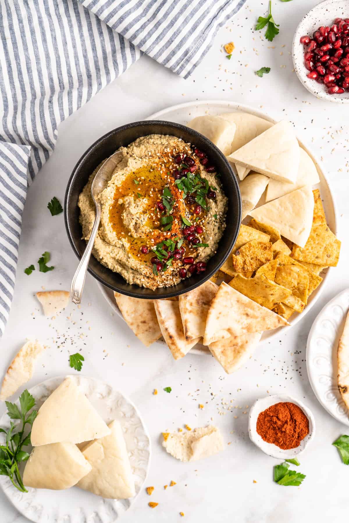 Overhead view of baba ghanoush in bowl with spoon and pita bread