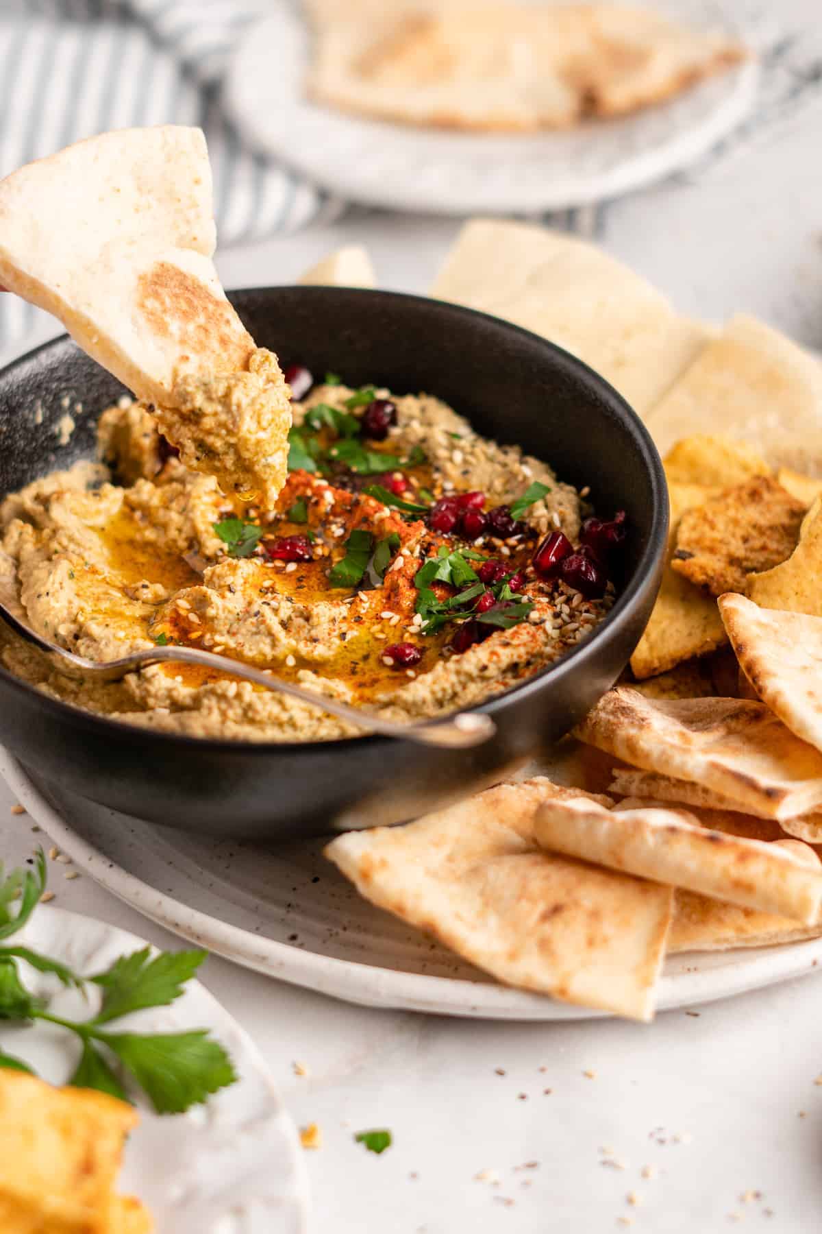 Baba ghanoush in bowl surrounded by triangles of pita on plate