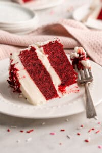 Slice of vegan red velvet cake on plate with fork