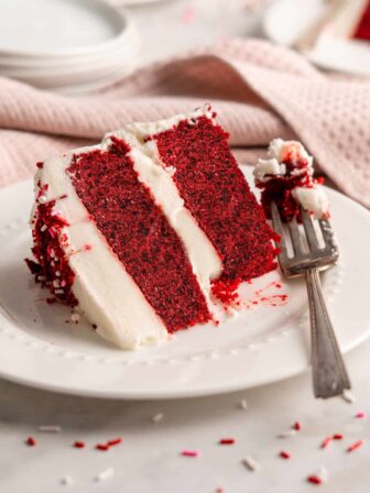 Slice of vegan red velvet cake on plate with fork