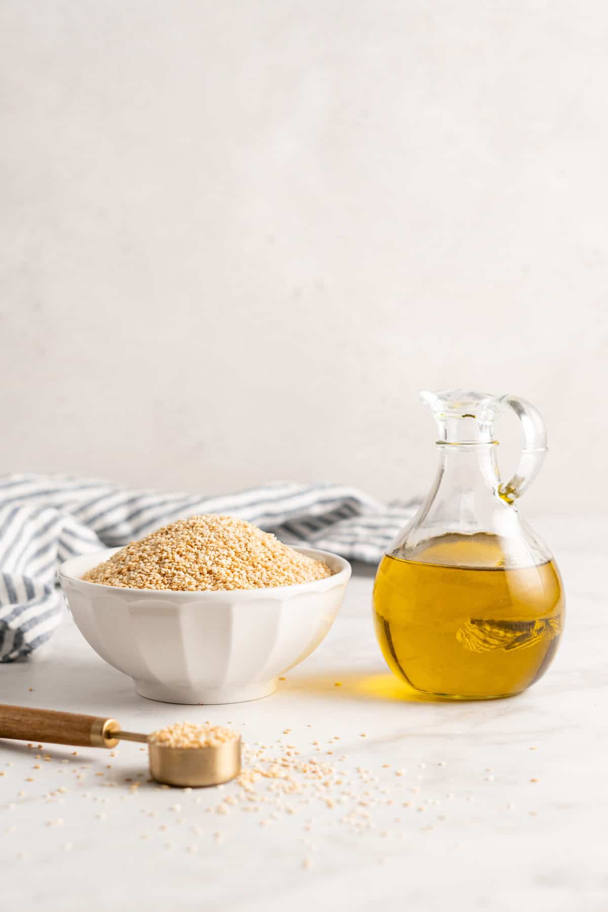 Bowl of sesame seeds and glass pitcher of olive oil