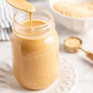 Spoon of tahini held over jar