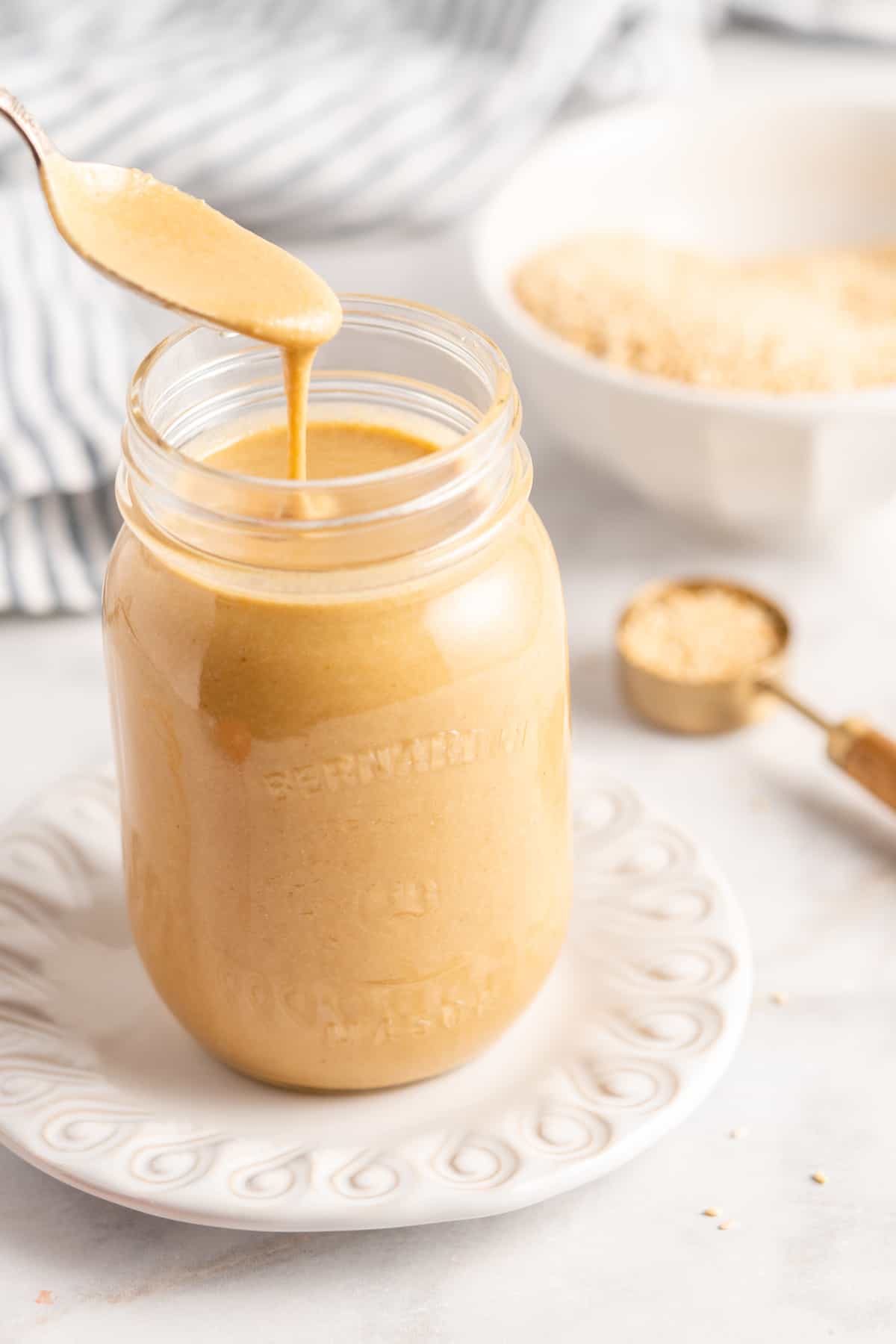 Spoon of tahini held over jar