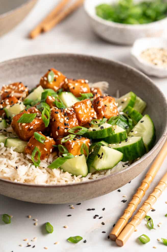Bowl filled with rice, cucumbers, and orange tofu