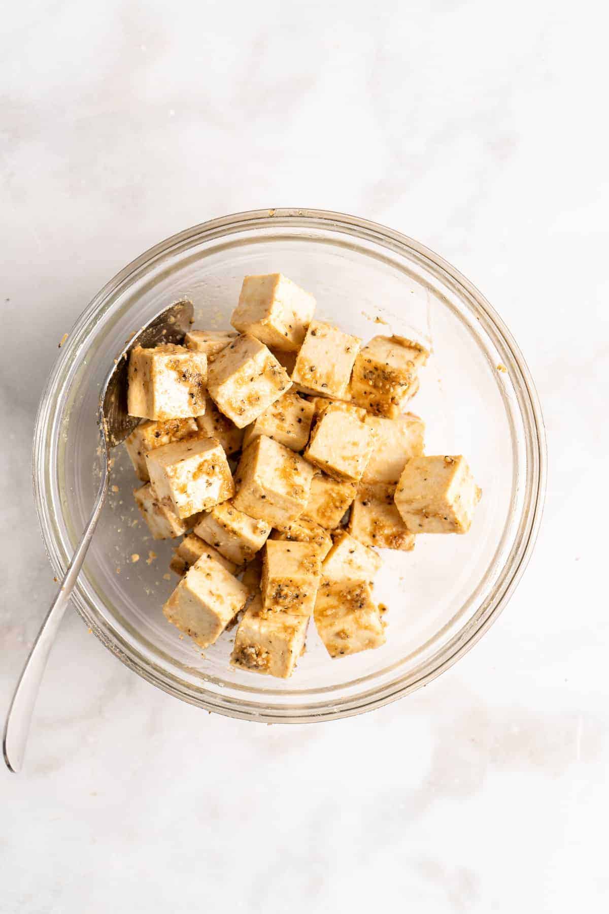 Overhead view of tofu in glass bowl with seasonings