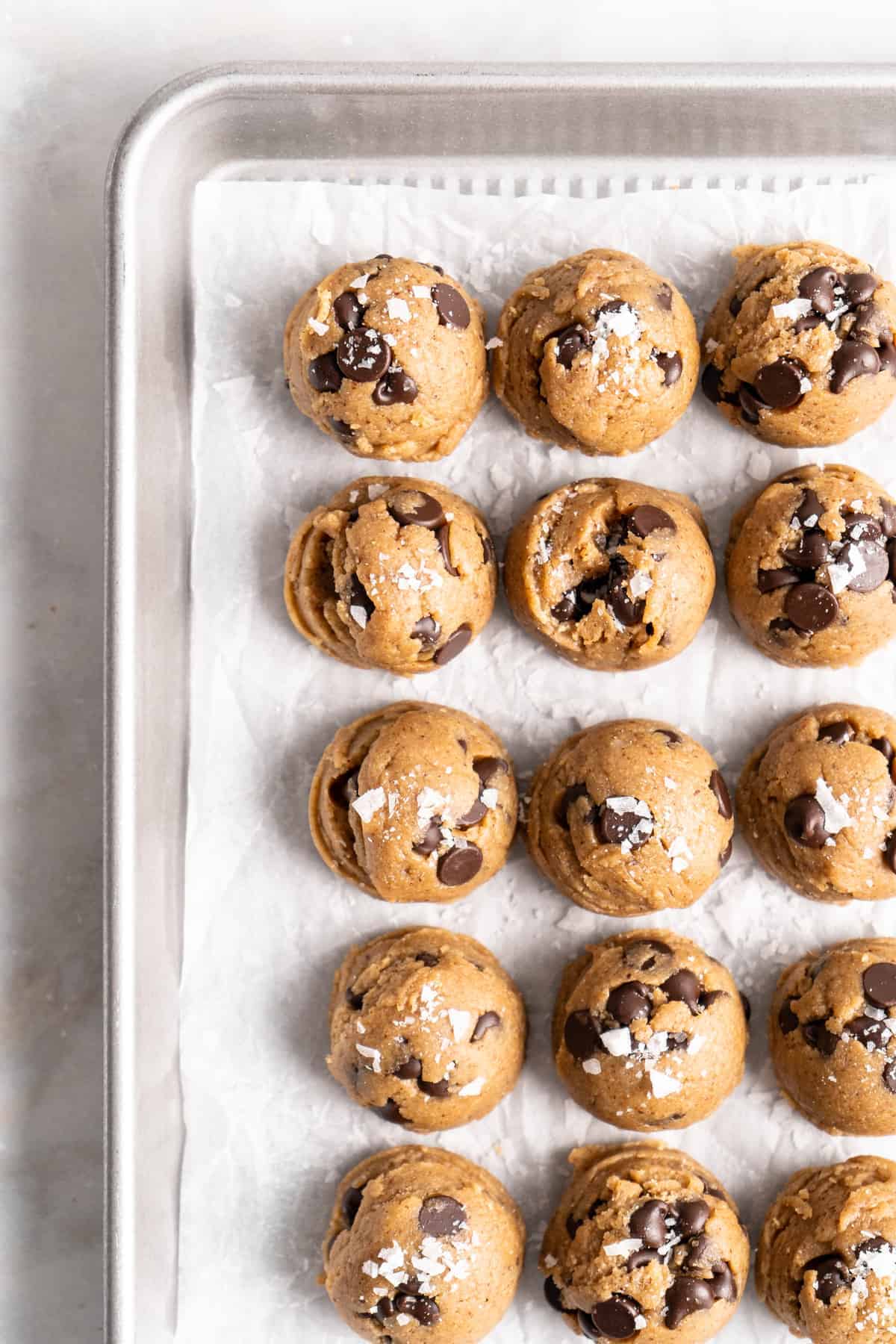 Overhead view of cookie dough balls arranged on parchment-lined baking sheet