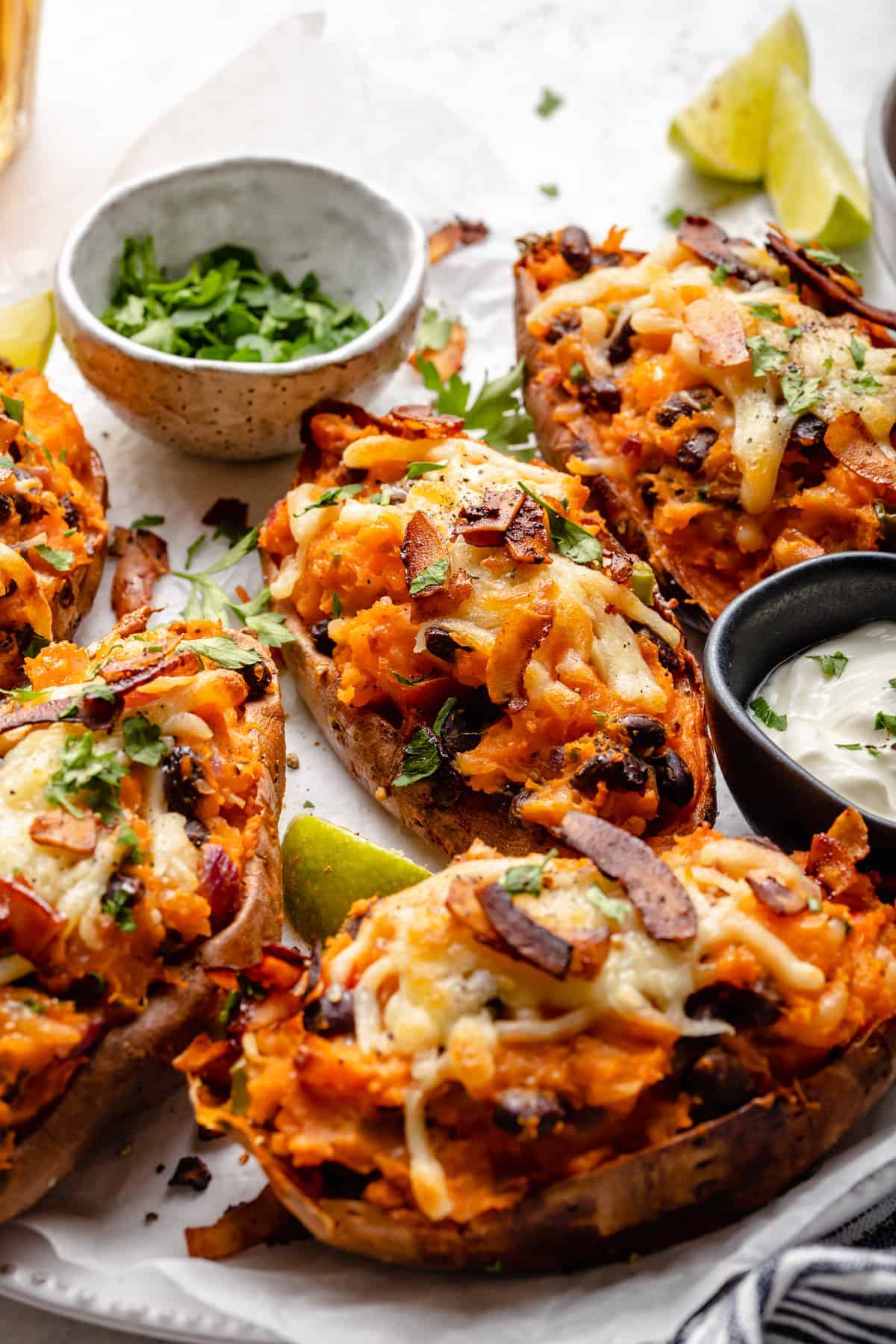 Loaded sweet potato skins on platter with bowls of cilantro and yogurt for garnish