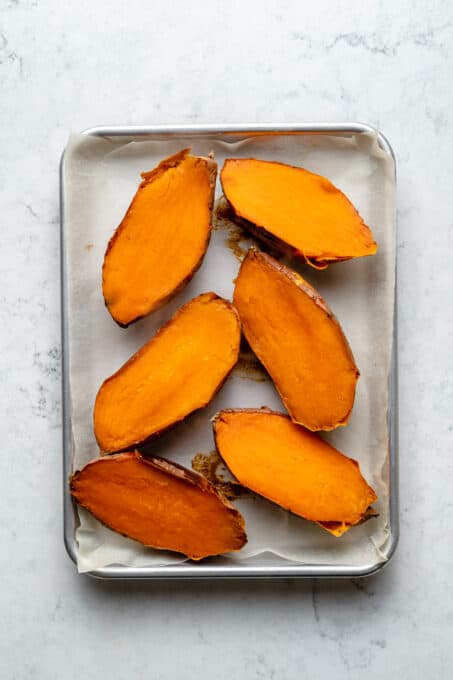 Overhead view of halved sweet potatoes on baking sheet