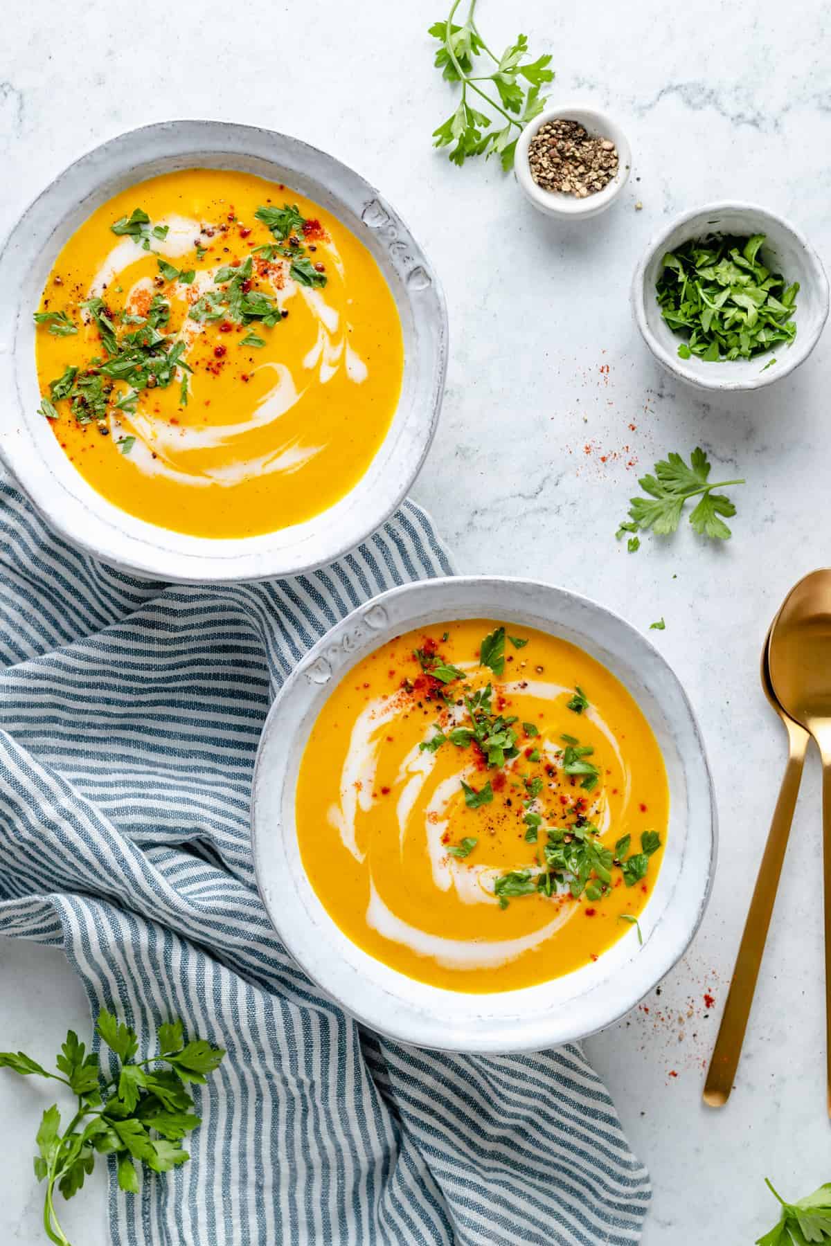 Overhead view of two bowls of roasted carrot soup swirled with coconut milk