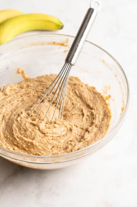 Banana bread batter in glass bowl with whisk