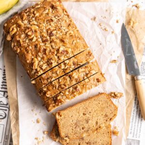 Overhead view of sliced loaf of banana bread set on parchment paper