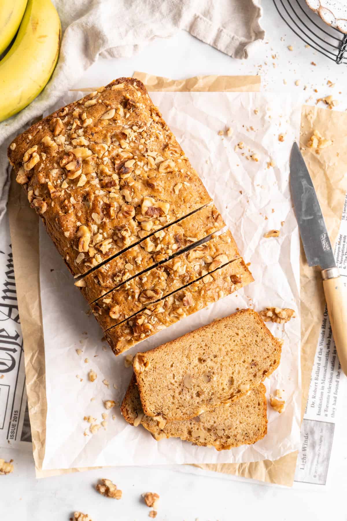 Overhead view of sliced loaf of banana bread set on parchment paper