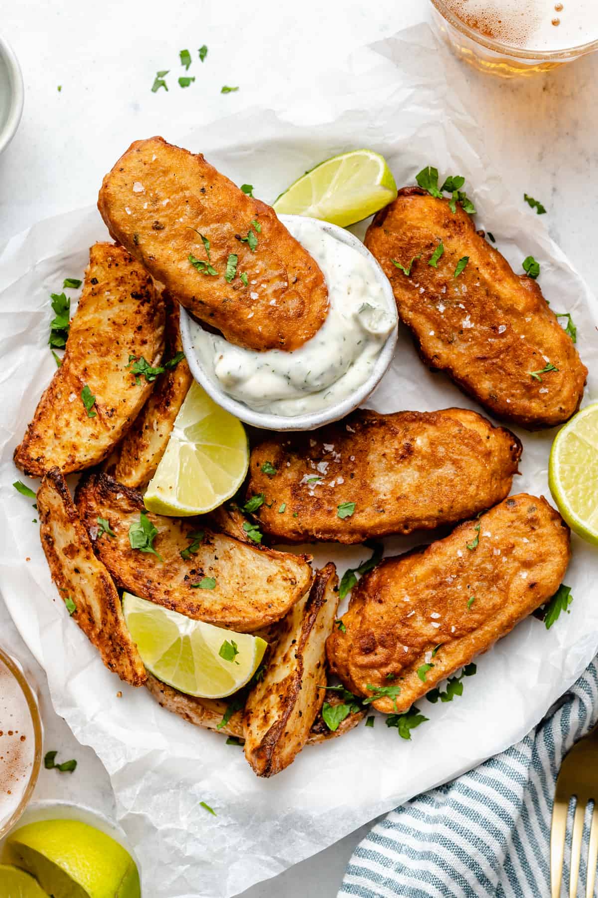 Overhead view of vegan fish sticks on parchment lined plate with one stick being dipped in sauce