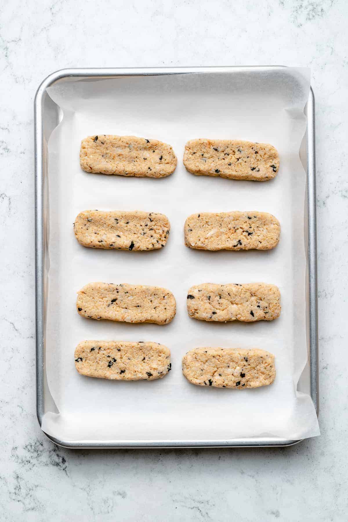 Overhead view of vegan fish sticks on parchment lined sheet pan