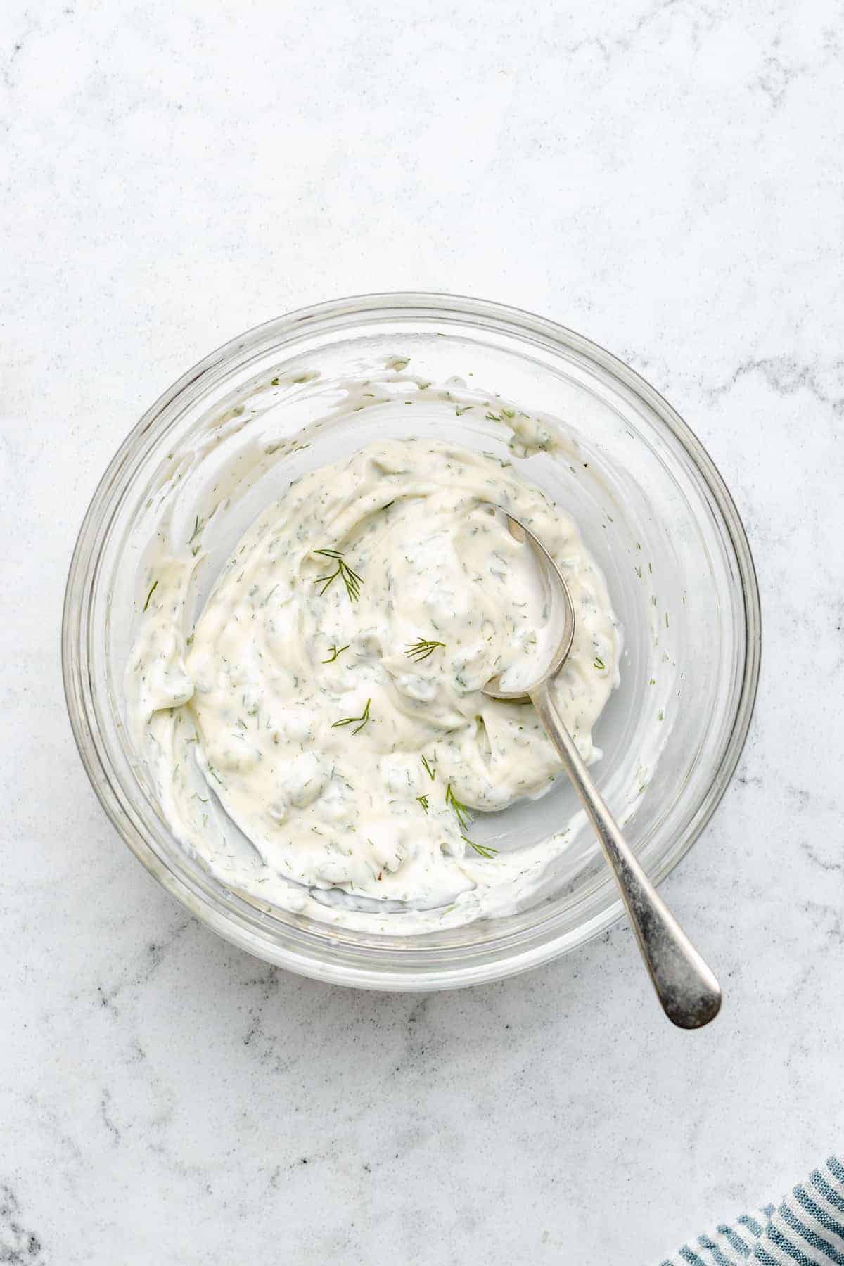 Overhead view of vegan tartar sauce in glass bowl with spoon