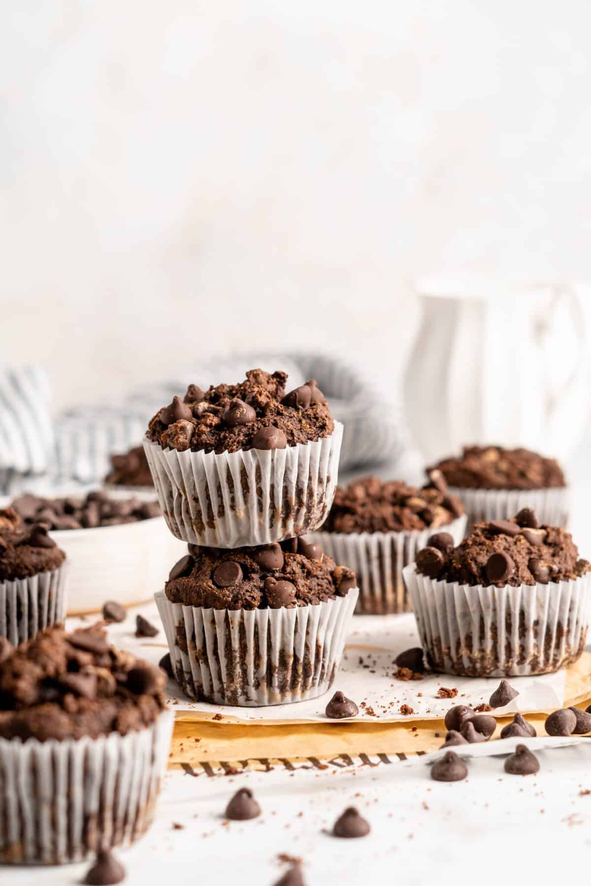 Two stacked Chocolate Banana Muffins, surrounded by additional muffins