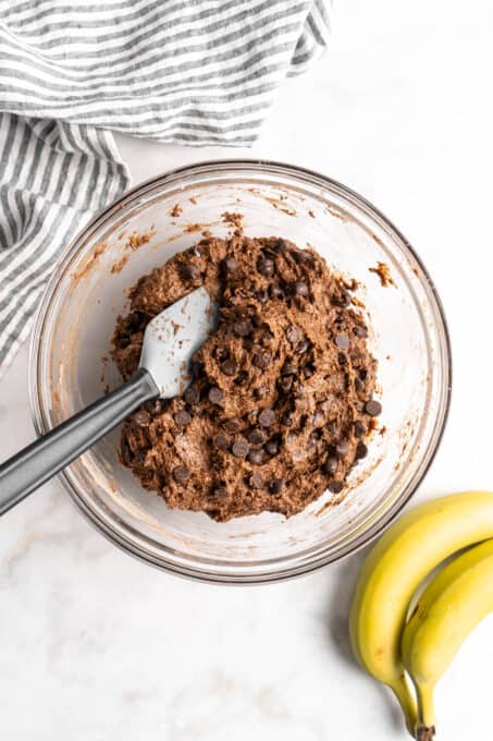 Chocolate muffin batter in glass bowl with spatula