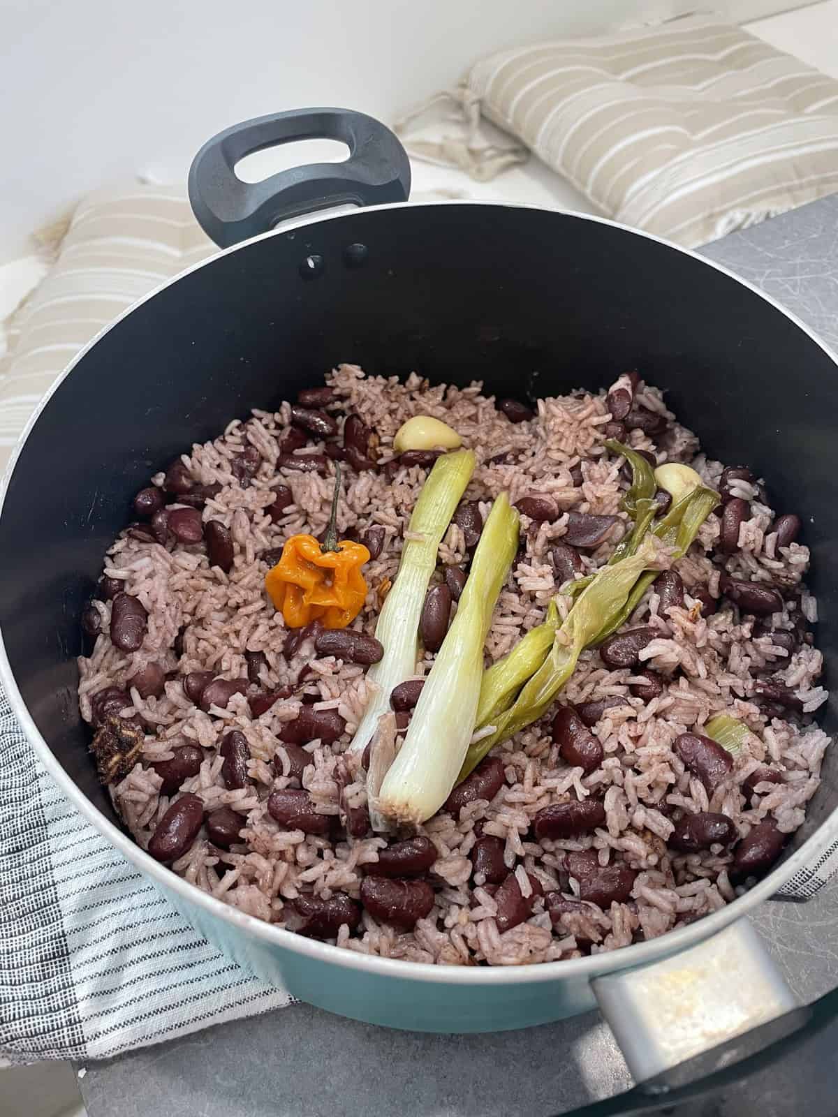 pot of cooked Jamaican rice and peas with scallion and scotch bonnet on top