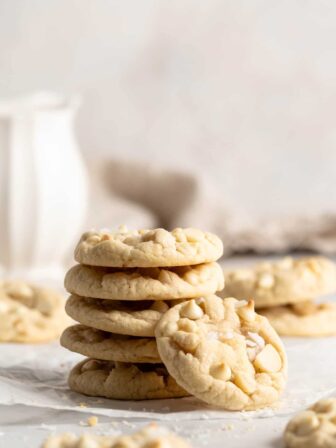Stack of White Chocolate Macadamia Nut Cookies with one cookie leaning against stack to show top