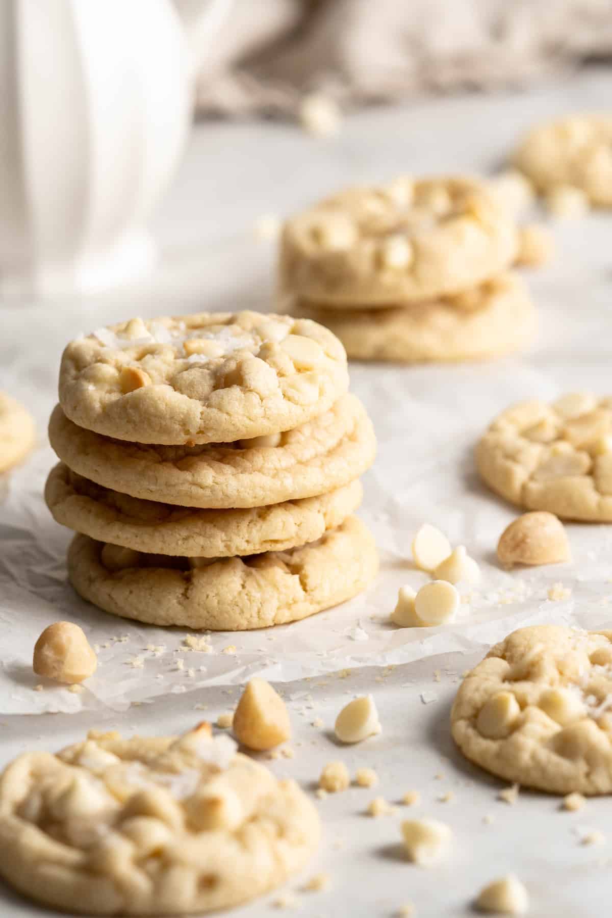 Stack of White Chocolate Macadamia Nut Cookies surrounded by additional cookies, nuts, and chips