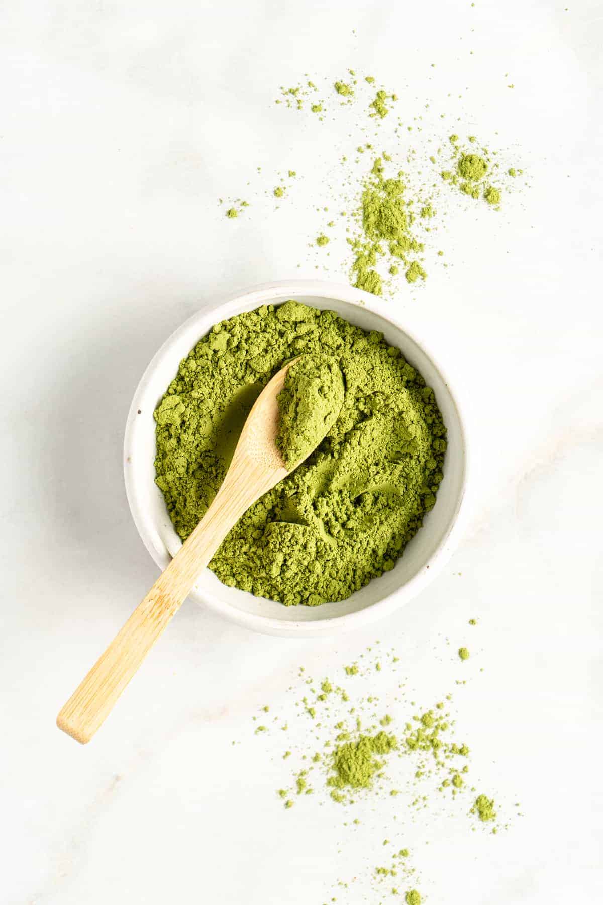 Matcha powder in white matcha bowl with wooden spoon