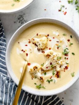 Overhead view of Roasted Cauliflower Soup garnished with cauliflower, red pepper flakes, and thyme
