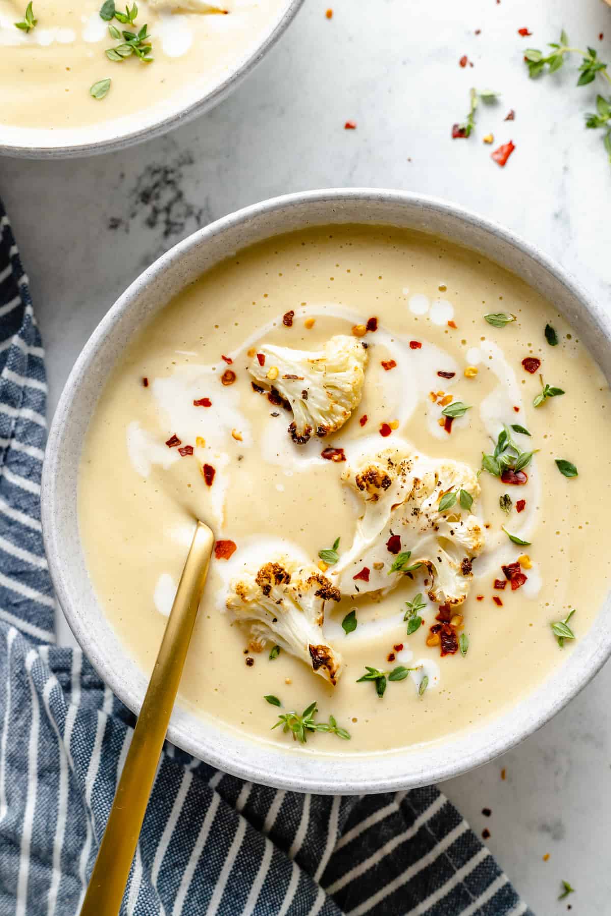 Overhead view of Roasted Cauliflower Soup garnished with cauliflower, red pepper flakes, and thyme