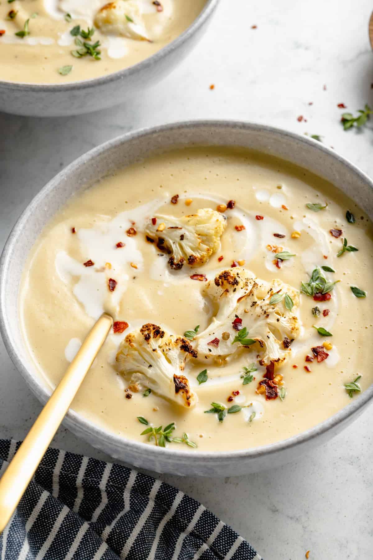 Roasted cauliflower soup in bowl with gold spoon